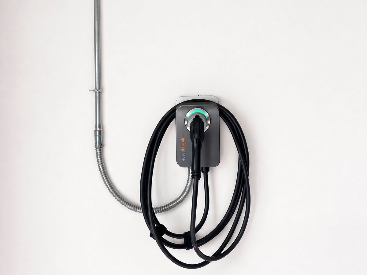 Wall-mounted Level 2 EV charger with conduit run and coiled charging cable in a garage