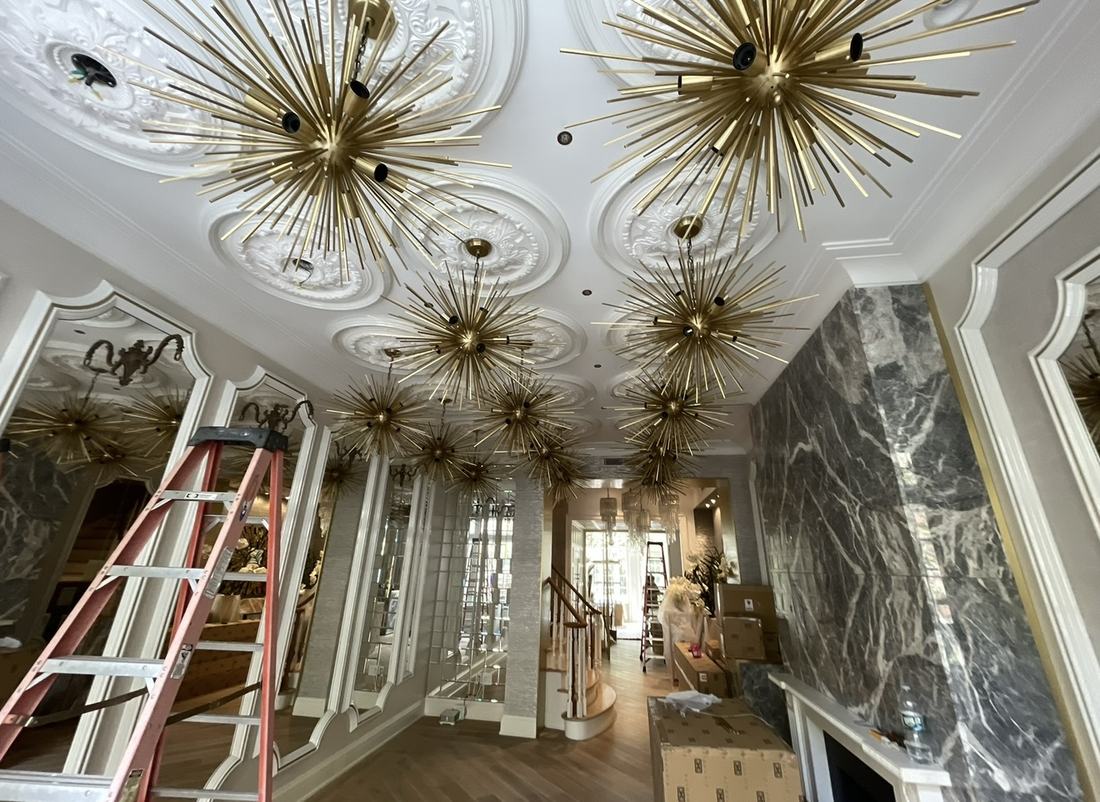 Gold sputnik chandeliers installed across a decorative plaster ceiling in a residential entry